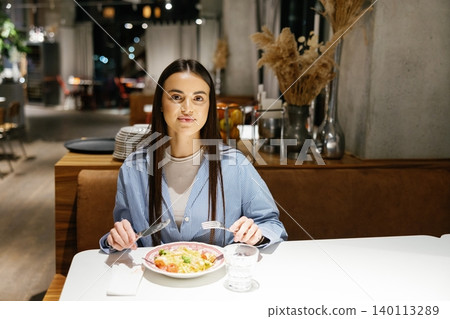 Young woman enjoying dinner eating pasta in restaurant Young woman enjoying dinner eating pasta in restaurant 140113289