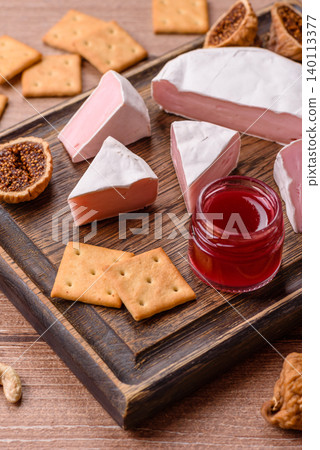 Pink Brie or Camembert cheese with honey, jam, figs, and crackers. Brie cheese Pink Brie or Camembert cheese with honey, jam, figs, and crackers. Brie cheese 140113377