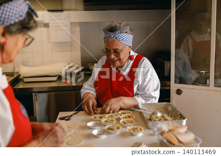 Happy senior Black woman preparing homemade food in a community kitchen for ageless vitality Happy senior Black woman preparing homemade food in a community kitchen for ageless vitality 140113469