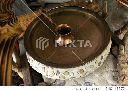 Copper cezve in hot sand for traditional Turkish coffee brewing Copper cezve in hot sand for traditional Turkish coffee brewing 140113572