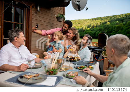 Multigenerational family having bbq party and taking selfie. Multigenerational family having bbq party and taking selfie. 140113574