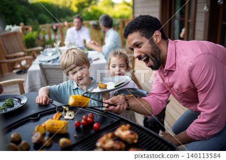 Man grilling meat and vegetable on grill during family summer garden party. Man grilling meat and vegetable on grill during family summer garden party. 140113584