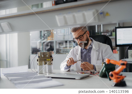 Robotics engineer working on prototype of modern robotic arm in laboratory office. 140113596