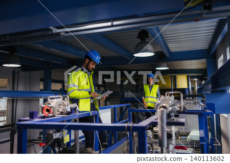 Industrial workers supervising automated manufacturing systems. 140113602