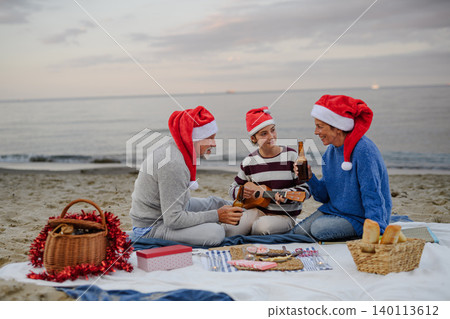 Family enjoying Christmas picnic on beach during winter holiday by the sea. 140113612