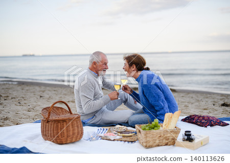 Senior couple in love having romantic picnic on beach by sea. Senior couple in love having romantic picnic on beach by sea. 140113626