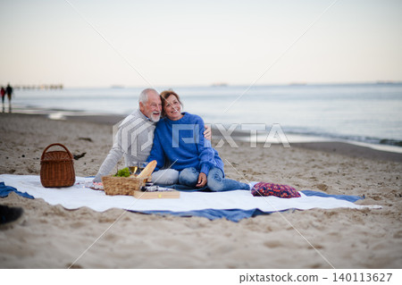 Senior couple in love having romantic picnic on beach by sea. Senior couple in love having romantic picnic on beach by sea. 140113627