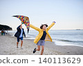 Senior man and his preteen granddaughter preparing kite for flying on sandy beach. 140113629