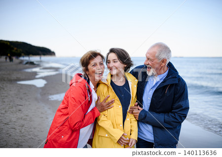 Grandparents walking with teenage granddaughter on beach during family vacation. Grandparents walking with teenage granddaughter on beach during family vacation. 140113636