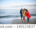 Grandparents walking with teenage granddaughter on beach during family vacation. 140113637