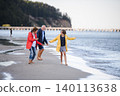 Grandparents walking with teenage granddaughter on beach during family vacation. 140113638