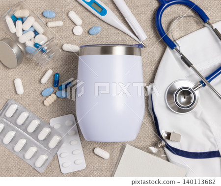 White 12 oz tumbler mockup with medical accessories and scrub uniform top view, blank template White 12 oz tumbler mockup with medical accessories and scrub uniform top view, blank template 140113682