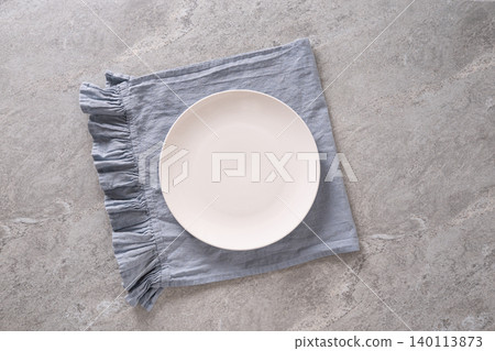 White plate on blue linen napkin top view White plate on blue linen napkin top view 140113873