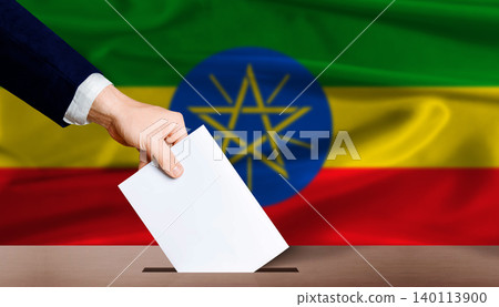 Hand placing a ballot in ballot box with the Ethiopian flag in the background. Ethiopia Parliamentary vote Hand placing a ballot in ballot box with the Ethiopian flag in the background. Ethiopia Parliamentary vote 140113900