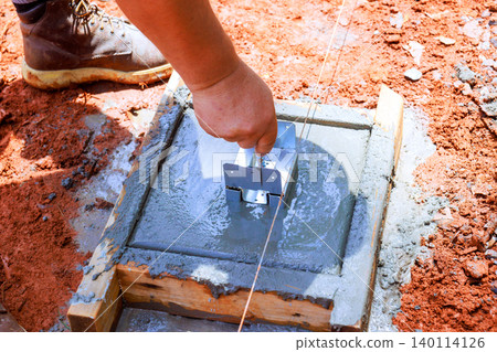 Worker uses tool to level freshly poured concrete at construction site Worker uses tool to level freshly poured concrete at construction site 140114126