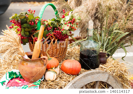 Autumn harvest bounty displayed on a rustic wagon wheel with wine and berries Autumn harvest bounty displayed on a rustic wagon wheel with wine and berries 140114317
