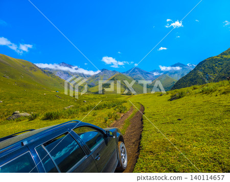 Dark colored car driving on dirt road in Kyrgyzstan valley Dark colored car driving on dirt road in Kyrgyzstan valley 140114657