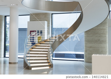Curved stone staircase with illuminated steps and glass railing in modern lobby Curved stone staircase with illuminated steps and glass railing in modern lobby 140114821