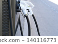 EV charging station in city close-up, road in background. Convenience and environmental benefits of electric vehicles, alternative fuel, car service. Accessible car energy resource in public areas 140116773