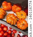 Colorful tomatoes ACCORDION ORANGE and some red tomatoes blurred, on the counter of a vegetable shop in wooden box, close-up. 140116774