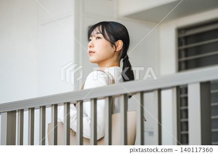 一位年輕的職業婦女離開公寓去上班。 一位年輕的職業婦女離開公寓去上班。 140117360