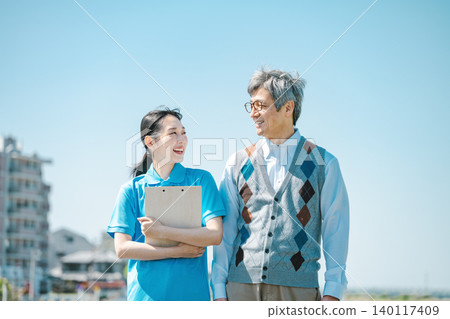 一位護理員和一位老人沿著河岸散步 一位護理員和一位老人沿著河岸散步 140117409