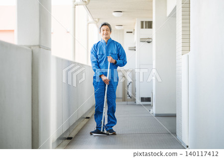 一位資深的男性建築管理員正在清潔公寓大樓的地板。 一位資深的男性建築管理員正在清潔公寓大樓的地板。 140117412