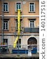 Historic Italian Building Facade Under Renovation With Yellow Construction Chute - Trieste City Centre, Scaffolding, Classic Ornate Windows, Urban Restoration Work Italy 140117516