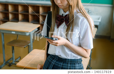 A female student using her smartphone in the classroom A female student using her smartphone in the classroom 140117819