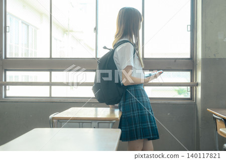 一名女學生站在窗邊。 140117821