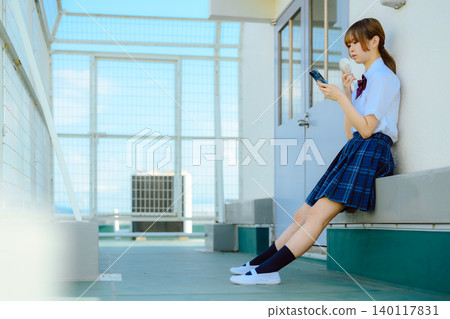 A girl in a school uniform is using her smartphone. A girl in a school uniform is using her smartphone. 140117831