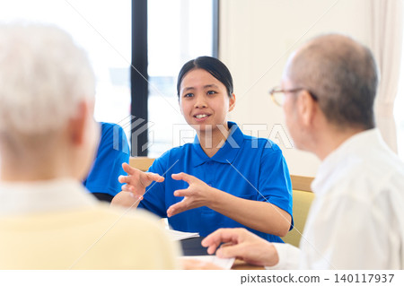 Southeast Asian caregiver explaining to Japanese senior Southeast Asian caregiver explaining to Japanese senior 140117937