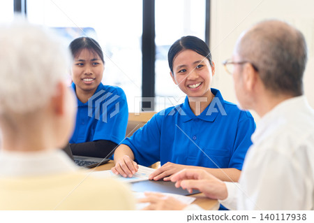 Southeast Asian caregiver explaining to Japanese senior Southeast Asian caregiver explaining to Japanese senior 140117938