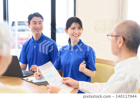 Asian caregiver explaining to Japanese seniors 140117944