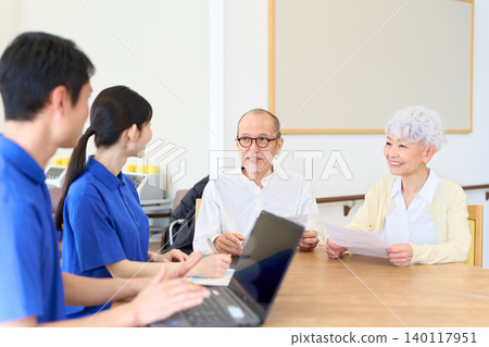 Asian caregiver explaining to Japanese seniors 140117951