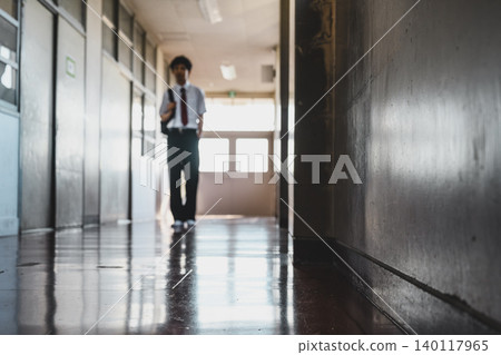 一個穿著校服的男孩走在走廊上 140117965