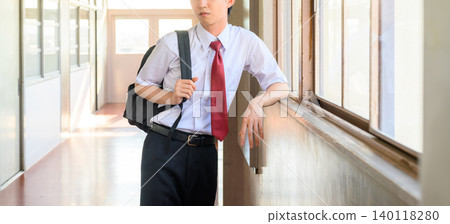 一名男學生正望著走廊窗外。 140118280