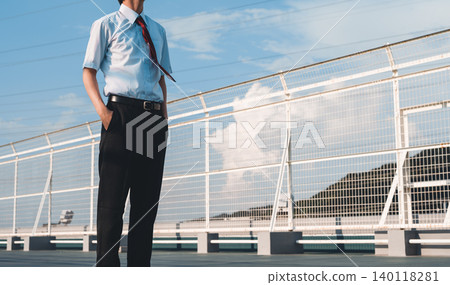 A businessman standing under a blue sky A businessman standing under a blue sky 140118281