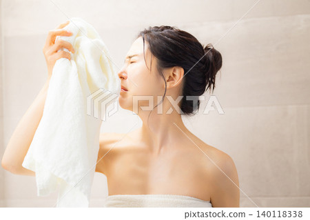 A young woman wiping her face with a towel after a bath. A young woman wiping her face with a towel after a bath. 140118338