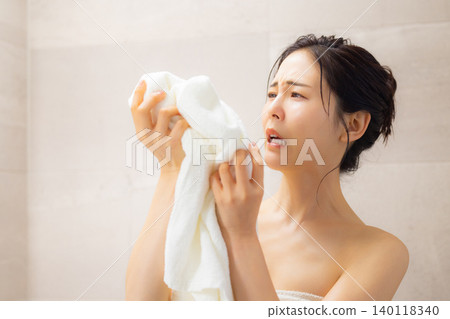 A young woman wiping her face with a towel after a bath. A young woman wiping her face with a towel after a bath. 140118340