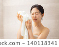 一位年輕女子洗完澡後用毛巾擦臉。 140118341