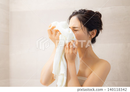 A young woman wiping her face with a towel after a bath. A young woman wiping her face with a towel after a bath. 140118342