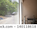 An old balcony service area has anti bird netting fixed along the open side, includes a small sink, narrow space, and metal lattice detail for building maintenance use. 140118618