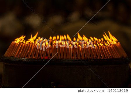 Close up rows of small burning candles capture soft smoke, flickering firelight, and an emotional low light moment of prayer and remembrance. Close up rows of small burning candles capture soft smoke, flickering firelight, and an emotional low light moment of prayer and remembrance. 140118619