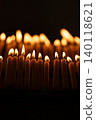 Close up rows of small burning candles capture soft smoke, flickering firelight, and an emotional low light moment of prayer and remembrance. 140118621