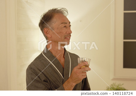Senior man drinking whiskey in his bedroom Senior man drinking whiskey in his bedroom 140118724