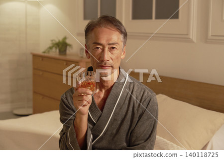 Senior man drinking whiskey in bedroom, portrait, looking at camera 140118725