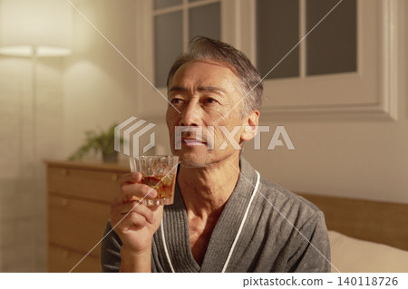 Senior man drinking whiskey in his bedroom Senior man drinking whiskey in his bedroom 140118726