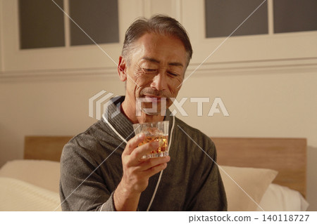 Senior man drinking whiskey in his bedroom Senior man drinking whiskey in his bedroom 140118727