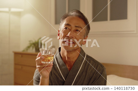 Senior man drinking whiskey in his bedroom Senior man drinking whiskey in his bedroom 140118730